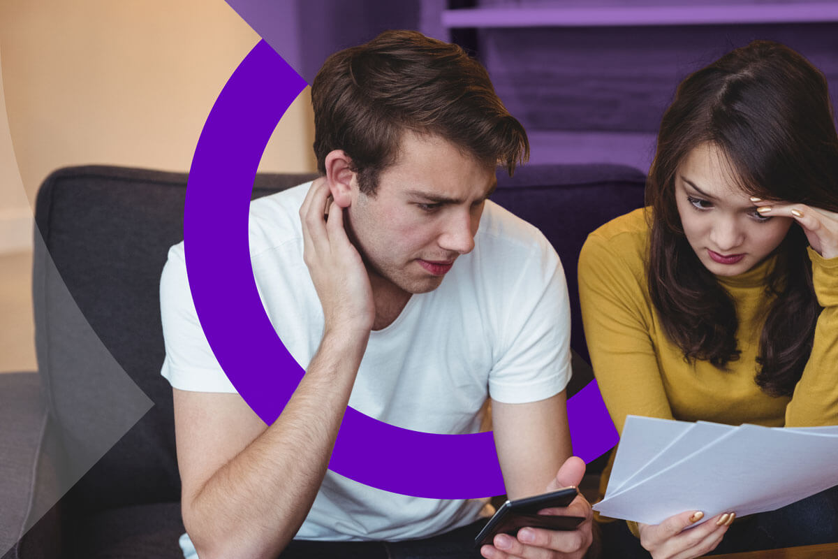 A couple looking at documents and holding a phone.