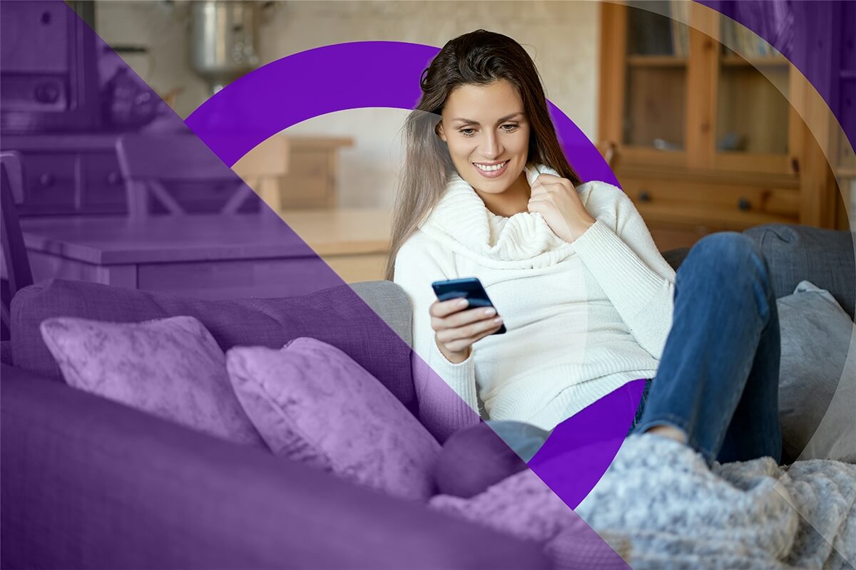 Young woman sitting on a couch with her phone.