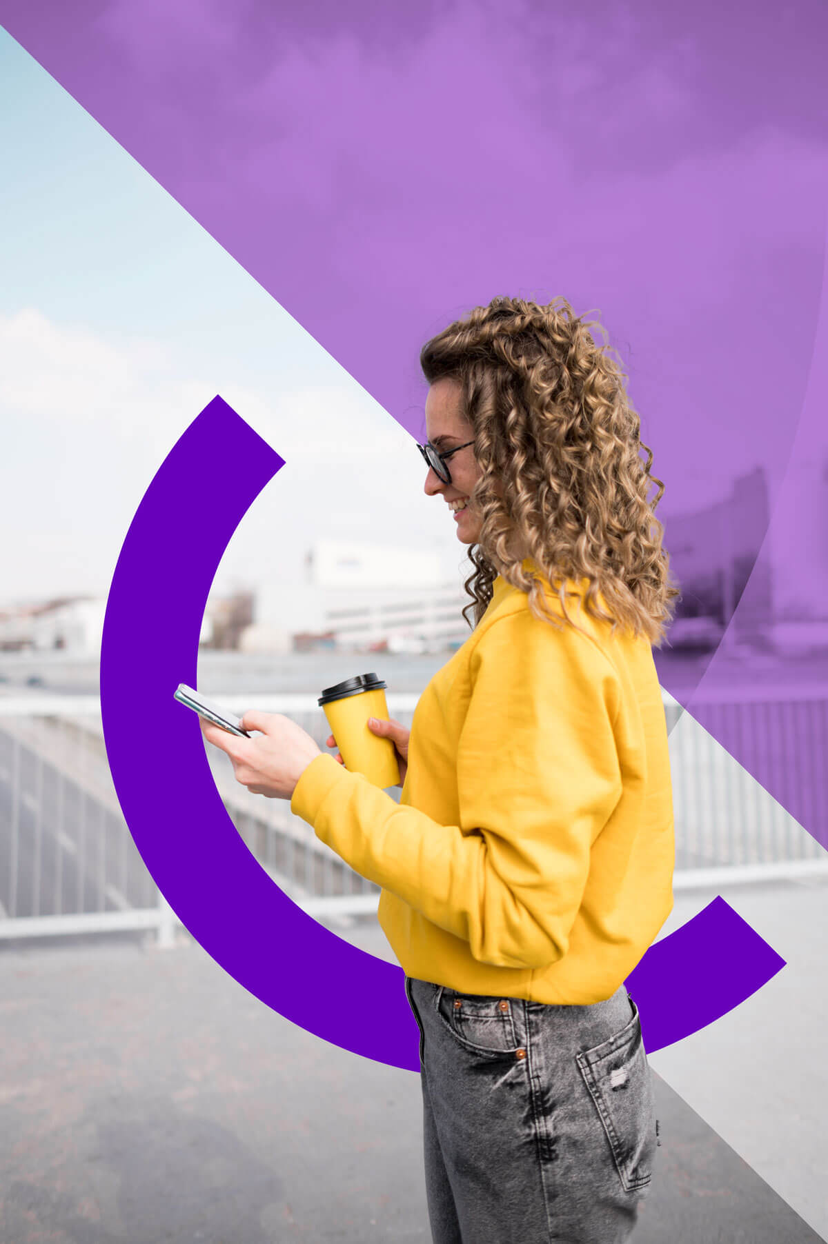 Woman in a yellow jumper looking at her phone outside.
